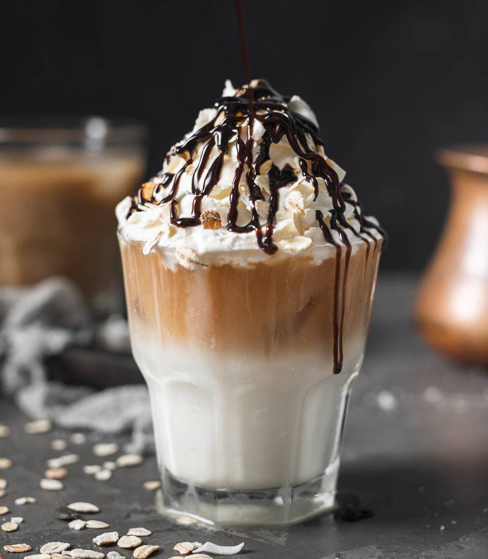 A layered coffee drink with whipped cream and a drizzle of chocolate.